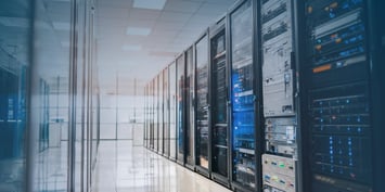 A data center hallway lined with server racks containing equipment and cables