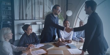 A group of business professionals shaking hands during a meeting, symbolising collaboration and partnership between business entities and EOR