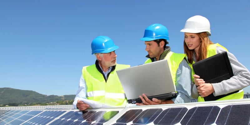 group of engineers on a roof with solar panels