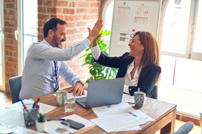 Man and woman in business attire high five each other