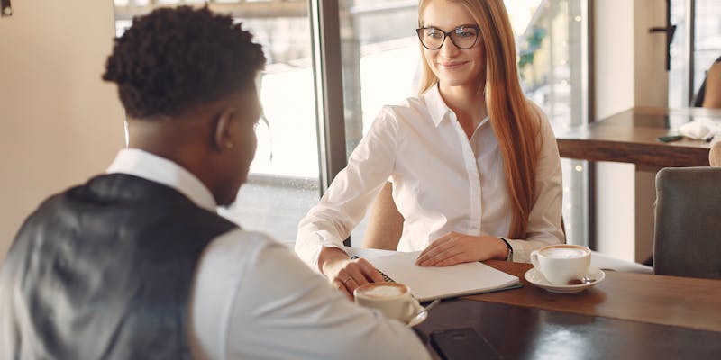 A woman interviewing a man in an office setting