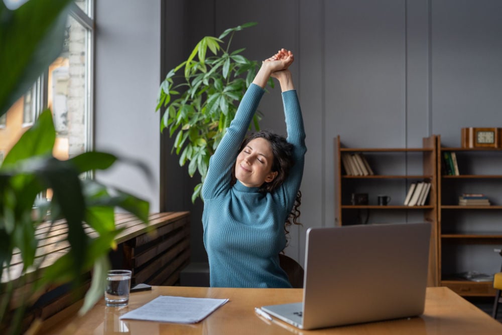 woman sitting at her desk and stretching