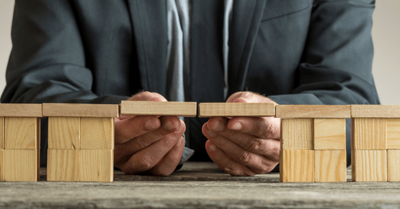 Person holds up two wooden blocks to connect more blocks placed on either side of their hands.