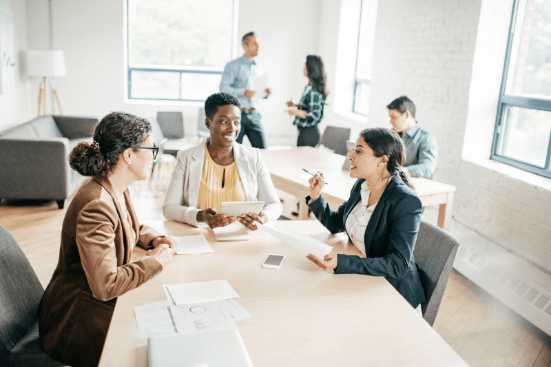 Ladies in business attire seated around a table, engaged in a conversation
