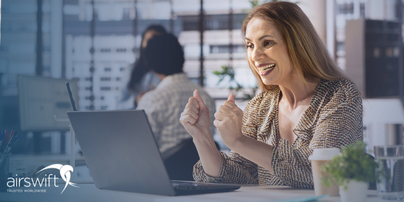 Smiling woman celebrates at her desk