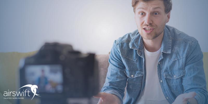 A man wearing a denim shirt sits on a sofa in front of a camera. He is talking animatedly, suggesting he is passionate about the subject he's speaking on.