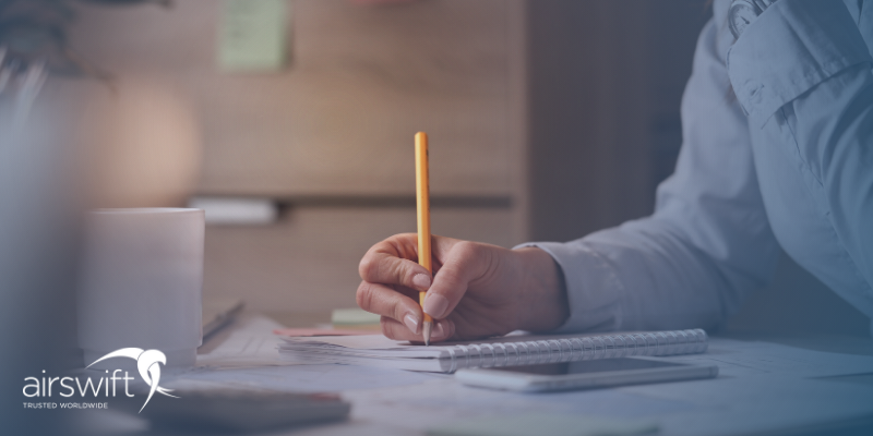 A man writes a resignation letter on a notepad at his desk