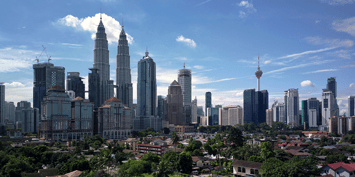 Kuala Lumpur skyline with the Petronas Twin Towers on the foreground and the KL Tower at the background against a clear blue sky